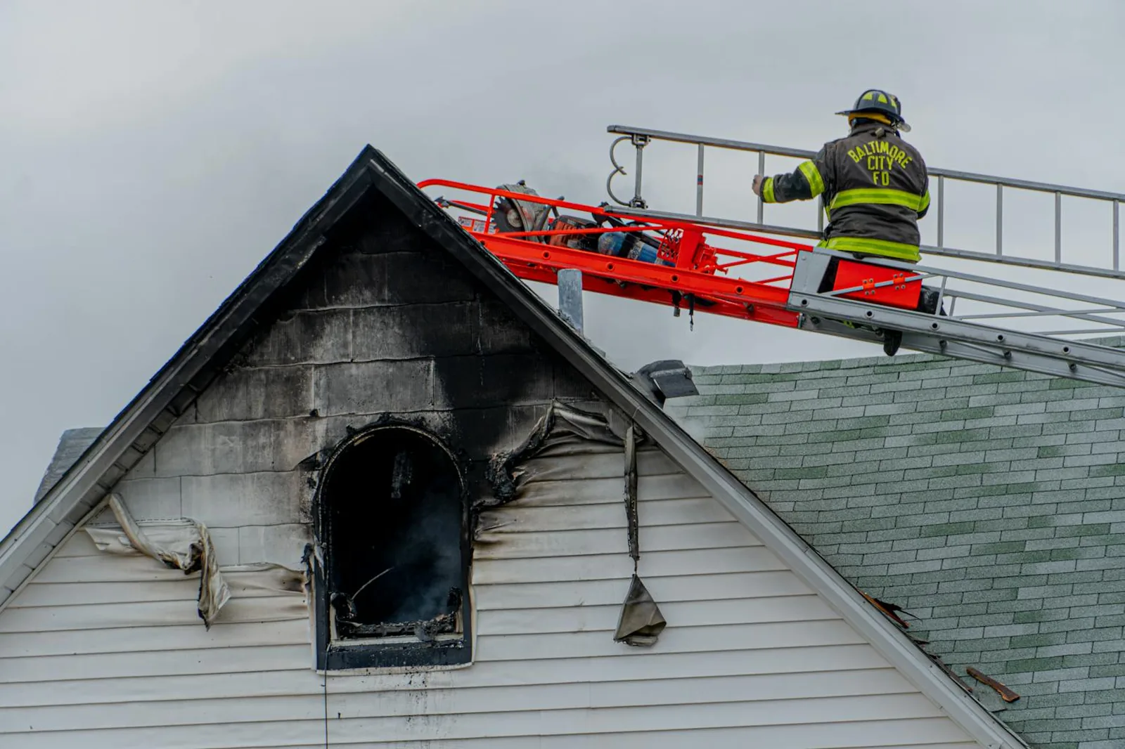 Firefighter on a ladder working a residential roof fire